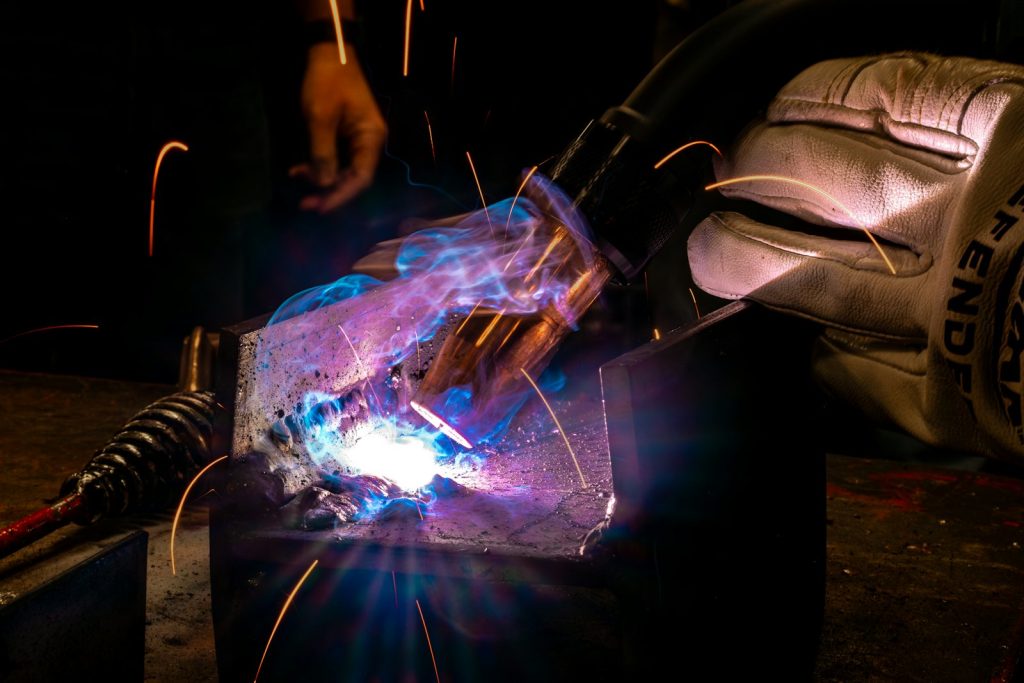 Gloved hand welding steel with sparks